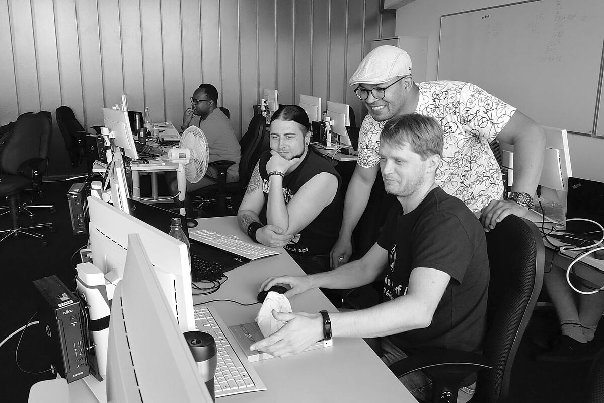 Männer in einem Klassenraum mit Monitoren bei der Arbeit
