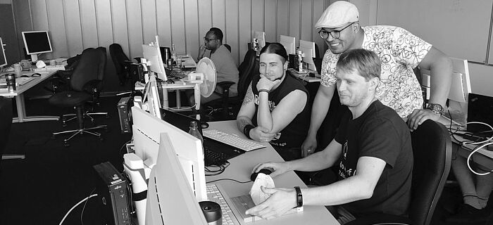 Klassenraum IT-Bildungshaus Männer in einem Klassenraum mit Monitoren bei der Arbeit