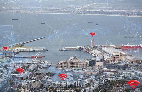Digitalisierung Hafenlogistik: Über der Ansicht eines Hafengeländes schweben WLAN-Icons