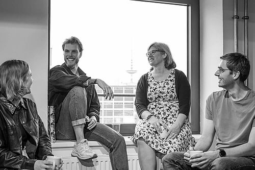 Vier Menschen machen Pause und stehen und sitzen im Fensterrahmen