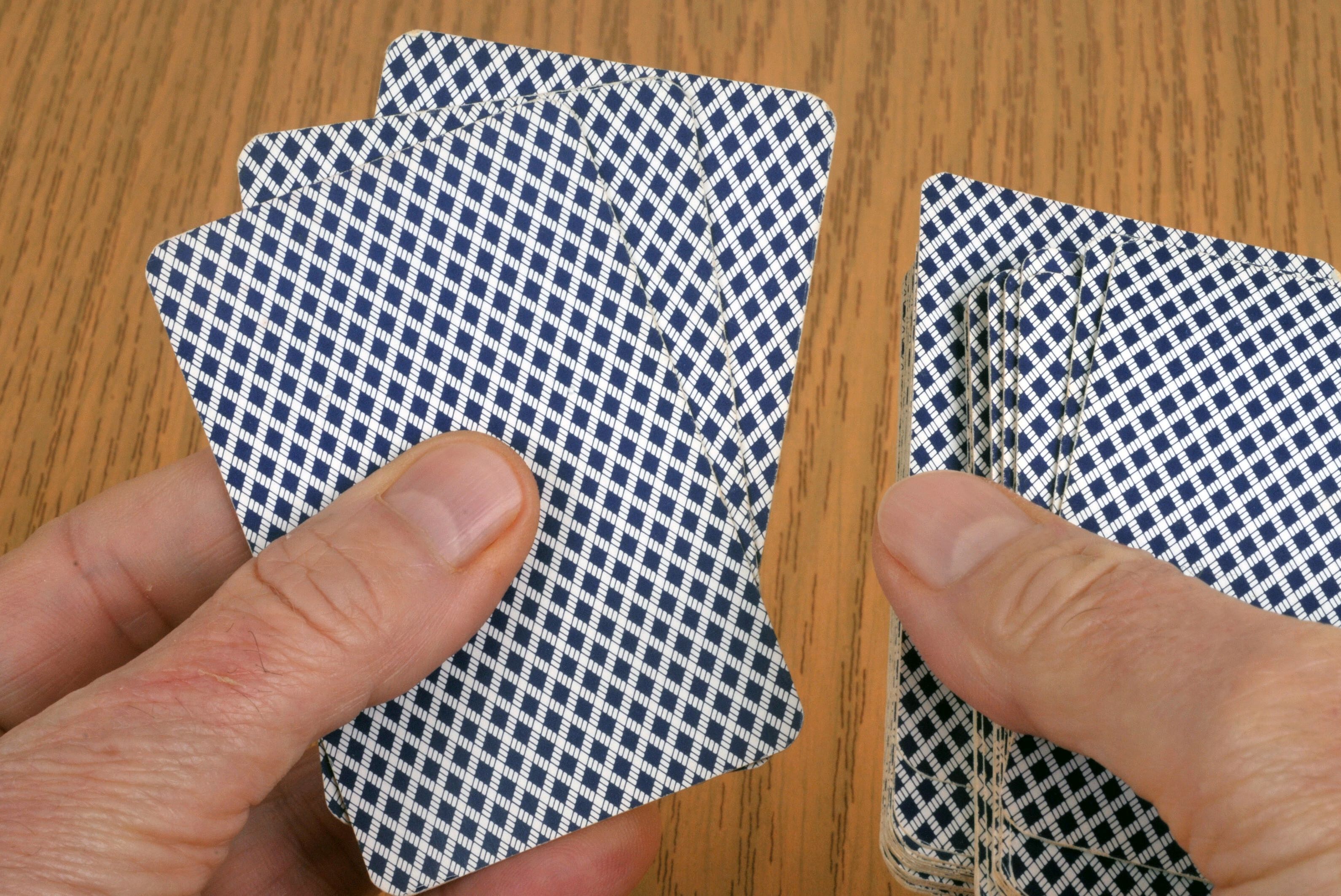Zwei Hände mit umgedrehten Poker-Karten