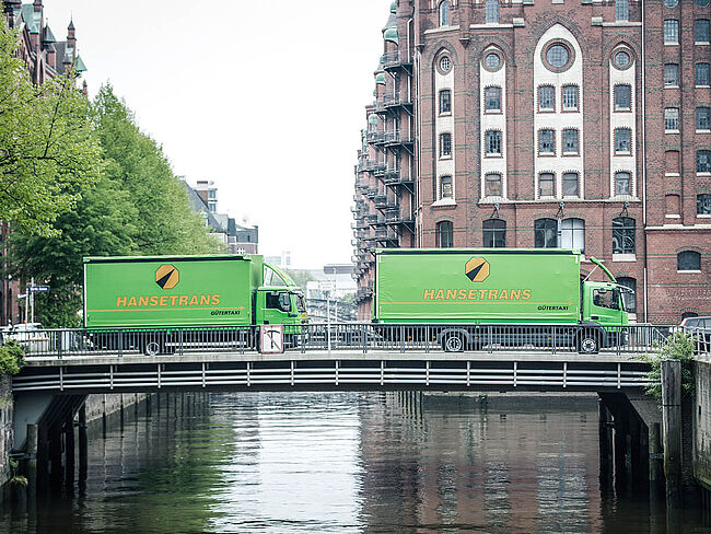 Foto von zwei grünen LKW's die eine Brücke überqueren.
