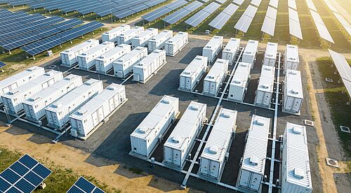 Auf einem Feld stehen Reihen von Sonnenkollektoren und Solaranlagen. 