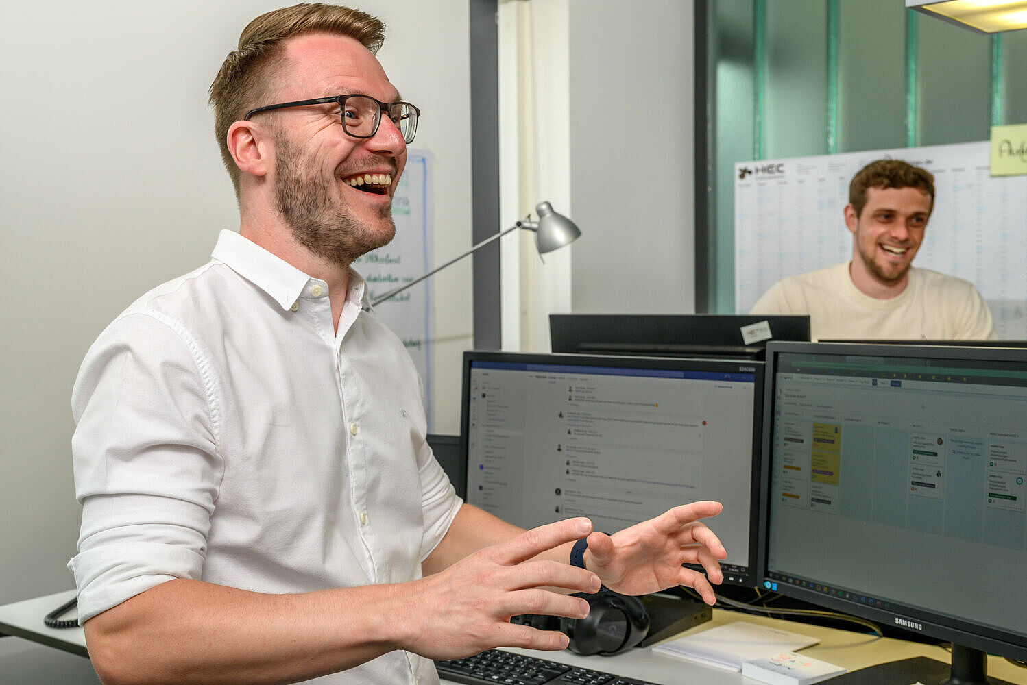 Ein Mann steht vor einem Schreibtisch mit Bildschirmen Ein Mann steht vor einem Schreibtisch mit Bildschirmen