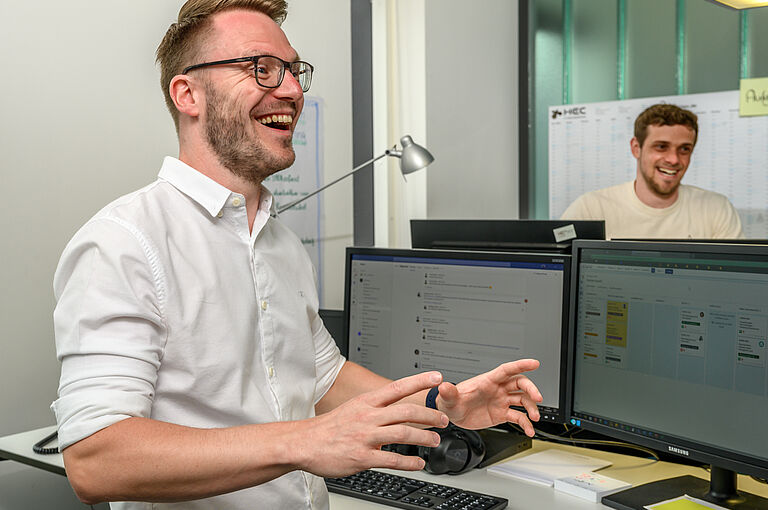 Ein Mann steht vor einem Schreibtisch mit Bildschirmen