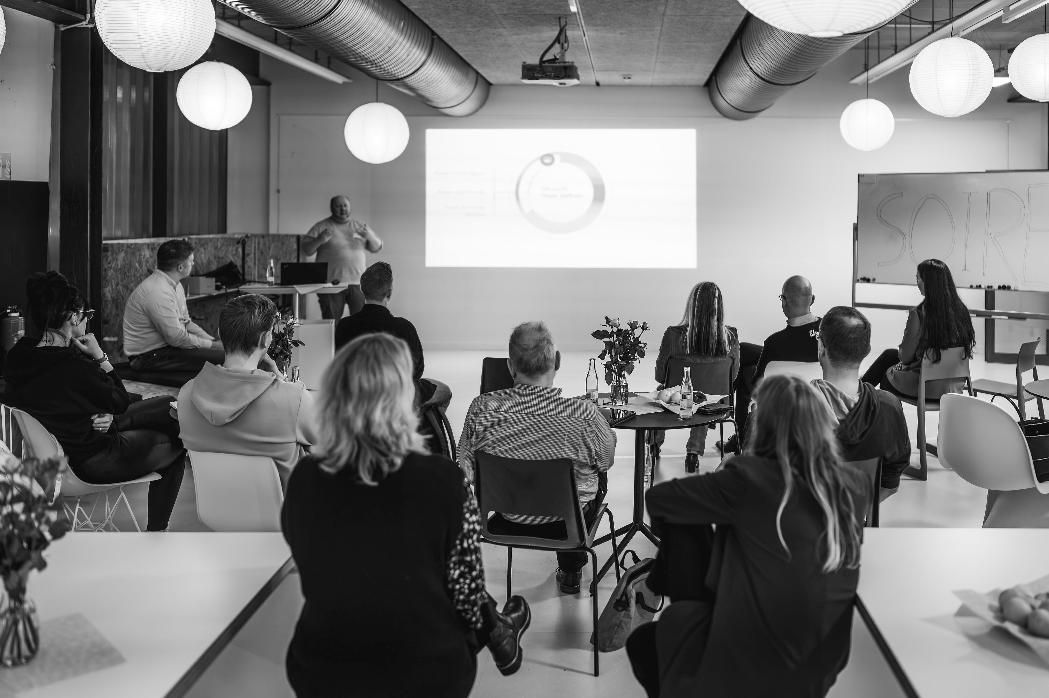 Personen sitzen in einem Raum und hören einem Vortrag zu.