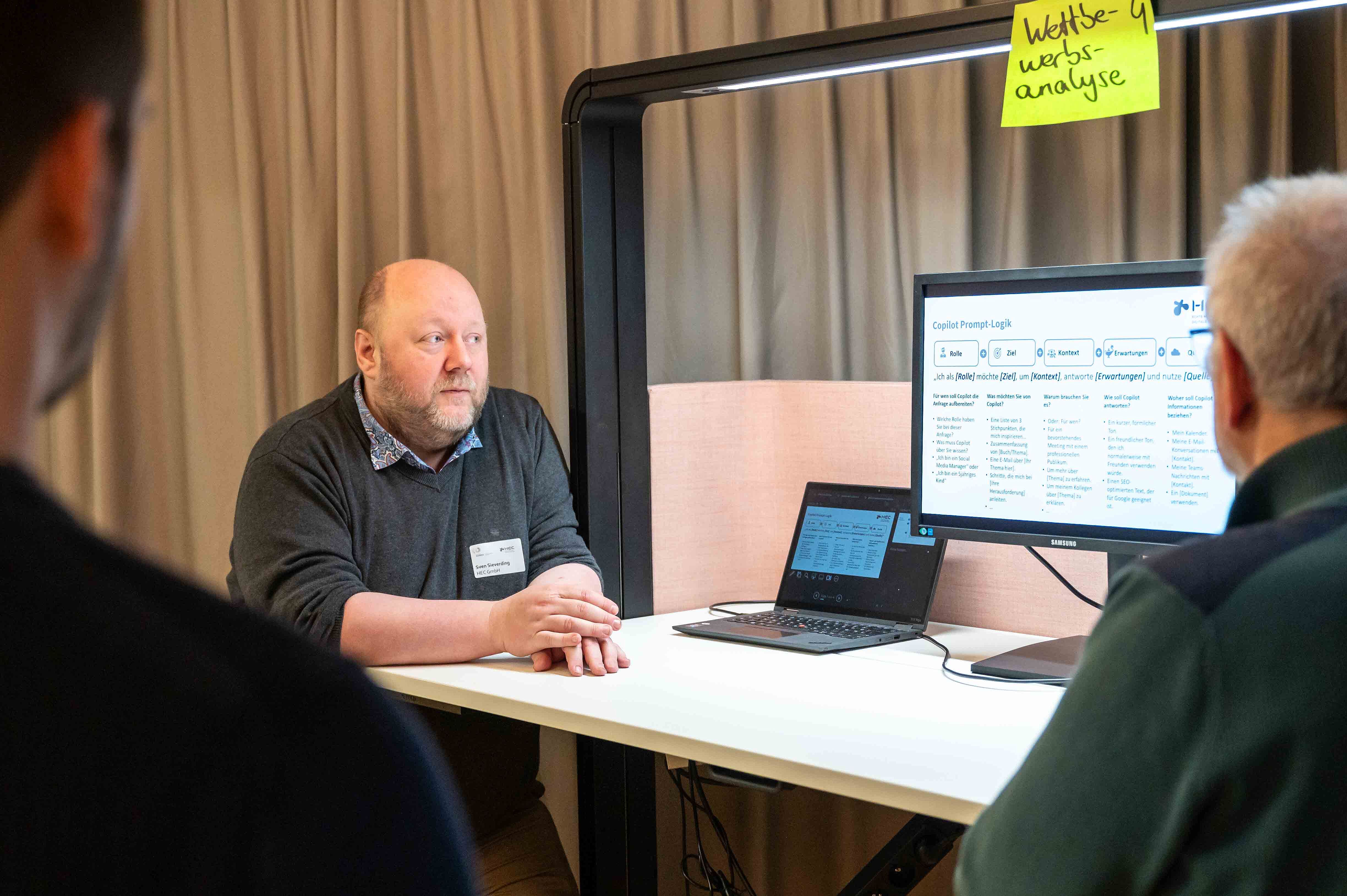 Sven Sieverding erläutert Teilnehmenden etwas am Bildschirm.