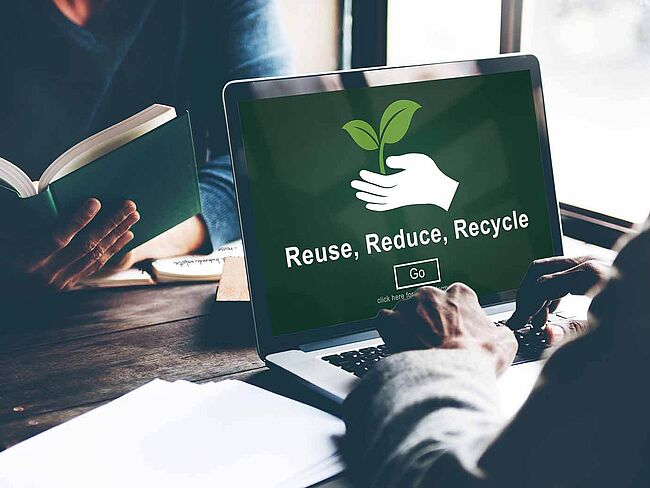 Laptop Bildschirm zeigt die Worte: Reuse, Reduce, Recycle