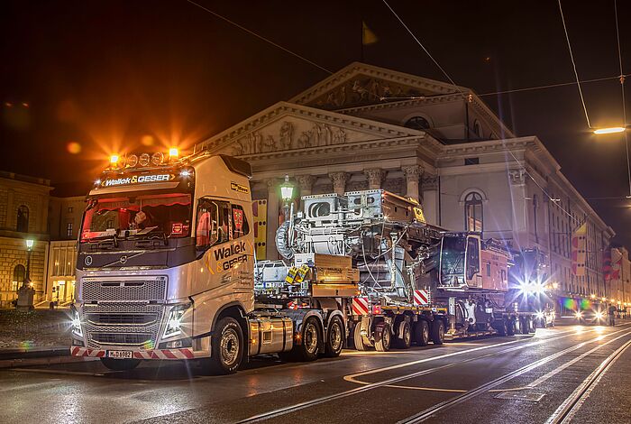 Ein Schwertransport fährt in der Nacht an einem großen, historischen Gebäude vorbei