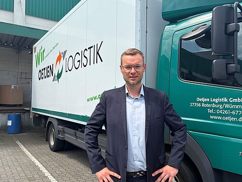 Ein Mann steht vor einem LKW mit der Aufschrift Oetjen Logistik.