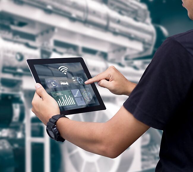 Person mit Tablet vor Maschine