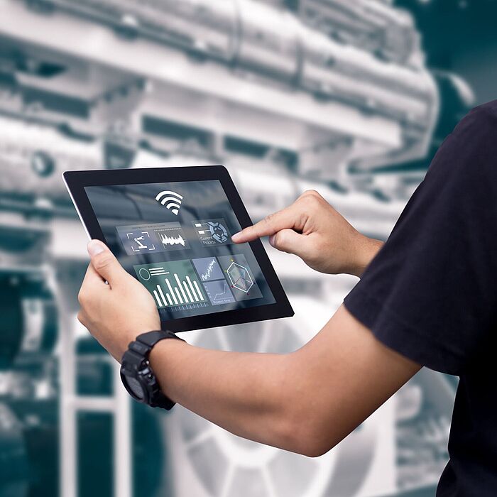 Person mit Tablet vor Maschine