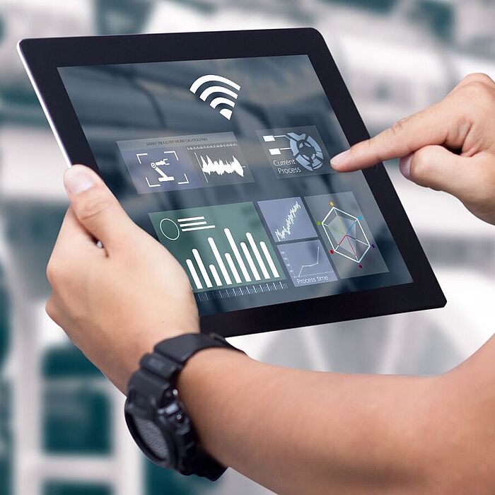 Person mit Tablet vor Maschine