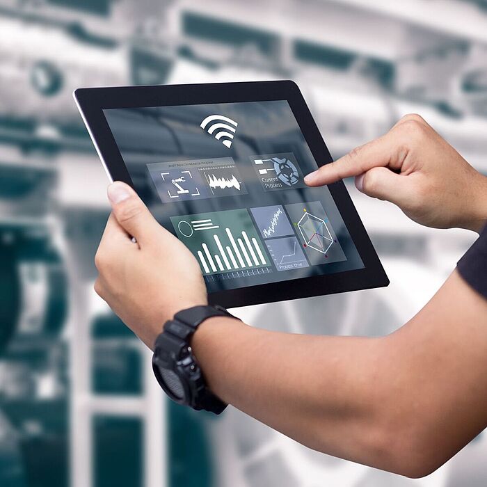 Person mit Tablet vor Maschine