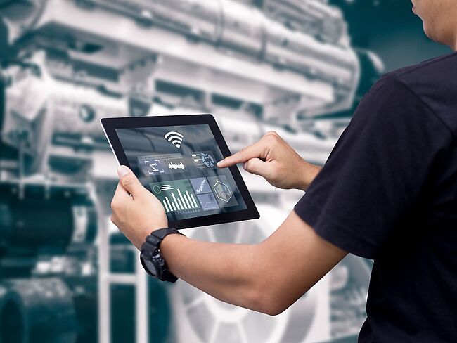Person mit Tablet vor Maschine