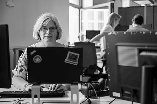 Eine Frau arbeitet an einem Laptop am Schreibtisch im Büro