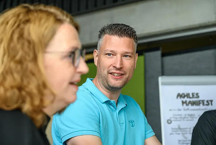 Mitarbeitende der HEC, vor einem Plakat mit dem Agilen Manifest