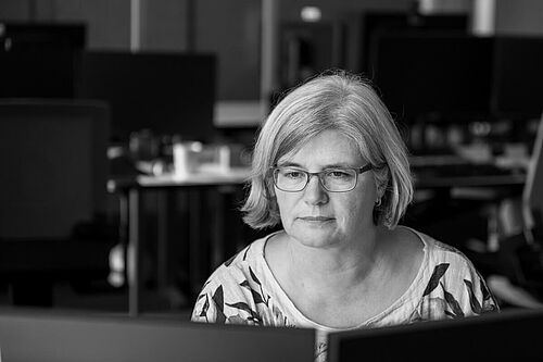 Arbeit am Schreibtisch mit Laptop und Monitor, eine Frau
