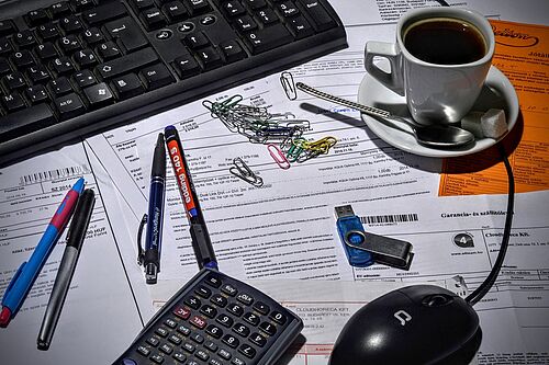 Schreibtisch mit Unterlagen und Computer. Foto von Oliver Menyhart auf Pixabay