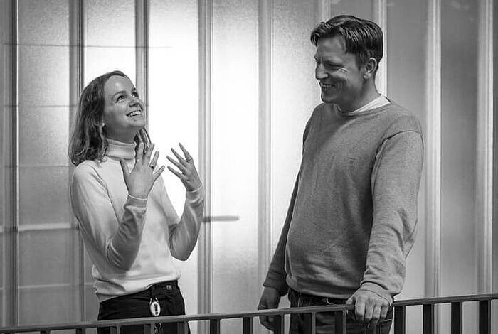 Ein Mann und eine Frau stehen auf einer Galerie im Foyer der HEC und sprechen angeregt mit einander.