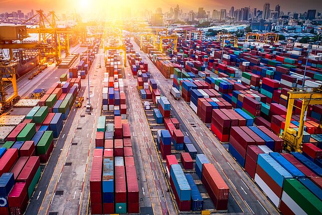 Containerterminal mit Sonnenuntergang im Hintergrund Containerterminal mit Sonnenuntergang im Hintergrund
